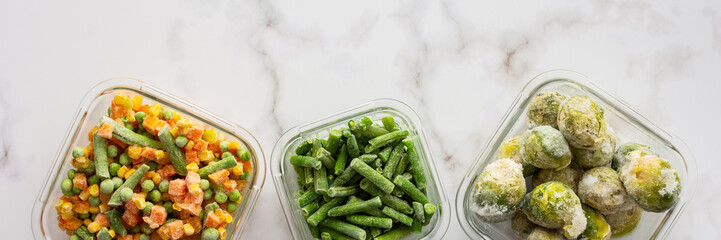 Frozen vegetables in containers banner , frozen cauliflower and asparagus beans, peas and corn, Brussels sprouts and carrots, mix of vegetables, top view, copy space