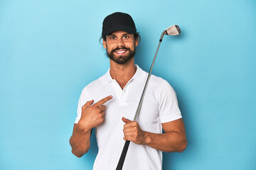 Long-haired golfer with club and hat smiling and pointing aside, showing something at blank space.