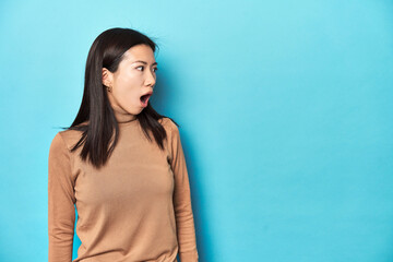 Fototapeta premium Young Asian woman in brown turtleneck, being shocked because of something she has seen.