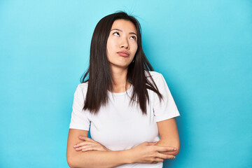 Young Asian woman in white t-shirt, studio shot, tired of a repetitive task.