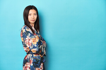 Elegant young Asian woman in floral kimono, studio backdrop.