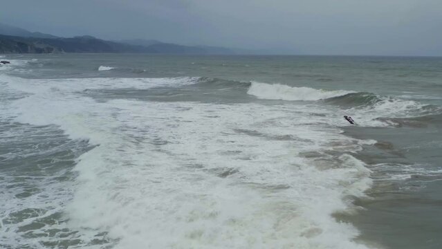 Waves crashing across itzurun beach in slow motion, aerial reverse dolly