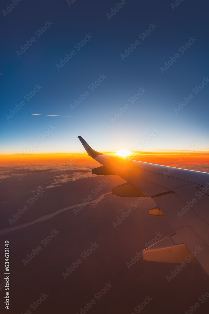 Poster Airplane flight in sunset sky over ocean water and wing of plane. View from the window of the Aircraft. Traveling in air.