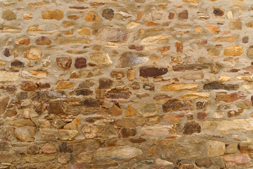 The texture of the old medieval wall of the house, lined with brown stone