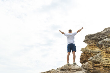 A man on a rock is engaged in energy practices, hands up