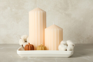 Candles and cotton in white plate on beige background