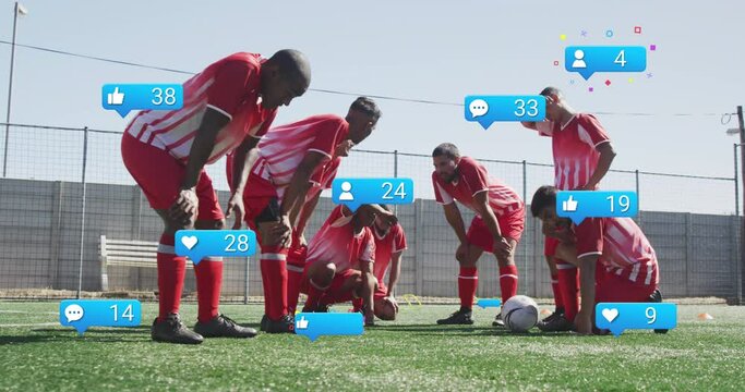 Animation of social media icons over tired diverse male soccer players taking break on sports field - Powered by Adobe