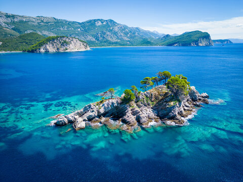Church on the rock on Katic islet in Petrovac na Moru Aerial View. Beaches and coastline of the Adriatic Sea at summer time. Natural landscapes of Montenegro. Balkans. Europe.