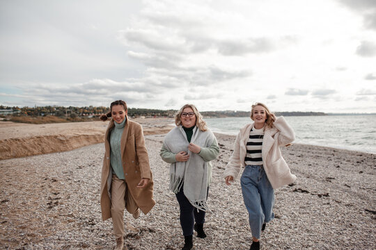Happy multicultural friends have fun , laugh and hug each other in the sea. People walking together, the beautiful plus size woman with  girls are smiling.