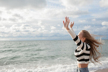 Young beautiful girl walking in the sand beach in cold weather day. Woman dressed warm clothes. The...