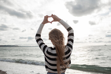 Young beautiful girl walking in the sand beach in cold weather day. Woman dressed warm clothes. The...