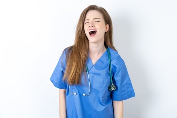 Young caucasian doctor woman wearing medical uniform angry and mad screaming frustrated and furious, shouting with anger. Rage and aggressive concept.