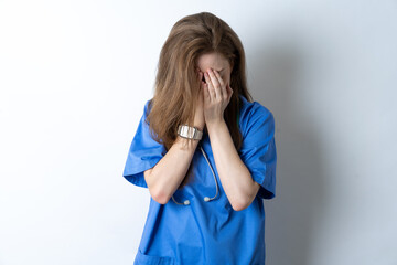 Young caucasian doctor woman wearing medical uniform covering her face with her hands, being devastated and crying. Sad concept