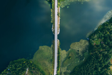 Aerial view of bridge asphalt road with cars and blue water lake and green woods in Finland.