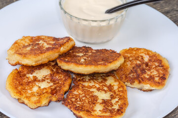 Сottage cheese pancakes with sour cream on dish close-up