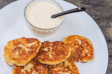 Cottage cheese pancakes with sour cream on dish close-up