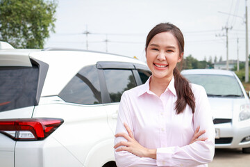 Beautiful smiling Asian woman standing in front of a car. Portrait of a car insurance company...