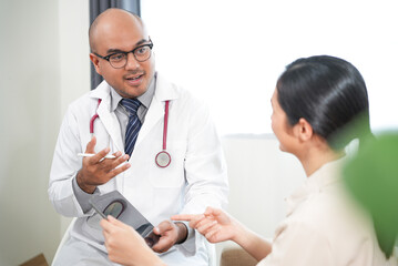 Fototapeta premium Beautiful asian women patient hurt hand consulting with Handsome asian professional doctor about pain in her hand feeling suffering and The doctor writing and analyzing her symptoms on the tablet.