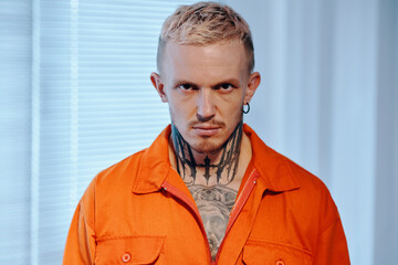 Portrait of aggressive suspect in orange uniform looking at camera