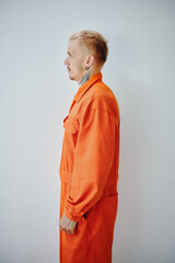 Profile portrait of arrested young man in orange jail uniform