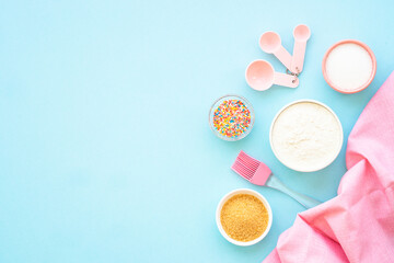 Food baking background on blue. Ingredients for cooking, flour, sugar, eggs. Flat lay with copy space.
