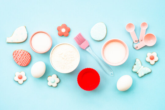 Easter baking background on blue. Flour, edds, sugar and gingerbread cookies. Top view with copy space.