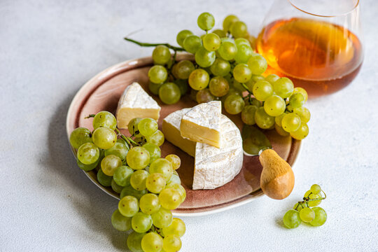 Cheese board with brie, green grapes and a glass of orange wine