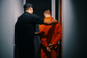 Police officer walking suspect to interrogation room, view from the back