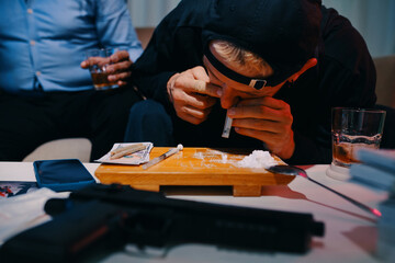Criminal in black hoodie snorting line of cocaine - obrazy, fototapety, plakaty