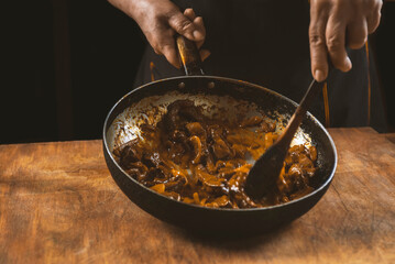 The cook prepares meat with vegetables and onion in a bowl . Oriental cuisine