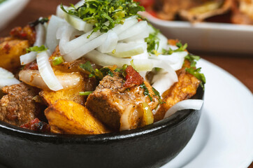 Beef stew with potatoes, carrots and herbs on black background with copy