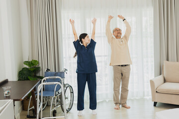 Asian nurse woman assisting old man warming up exercises for the upper body inside the nursing...
