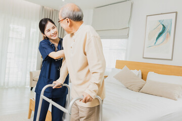 Smiling nurse woman helping senior Asian man to walk around the nursing home, use walker with strong health and Help and care concept
