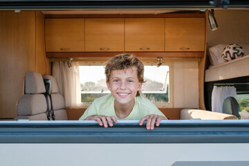 Delighted boy behind caravan window