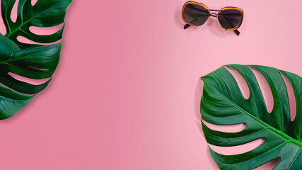 Tropical leaves with sunglasses on pink background. Empty space flat lay. Creative minimal summer concept. 