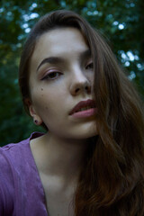 Fototapeta premium portrait of a beautiful, calm woman walking in the park in a lilac dress