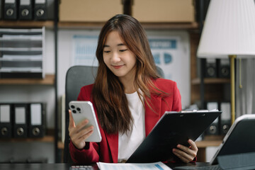 Business women hand working with smartphone and laptop computer with documents on office desk in modern office.