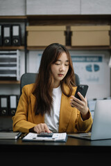 Businesswoman working with smartphone and using a calculator to calculate the numbers of static in...