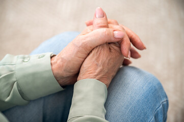 Mature retired woman with folded hands on knees