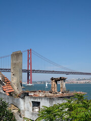 The "Ponte 25 de Abril" bridge in Lisbon, Portugal, with some ruins in the foreground