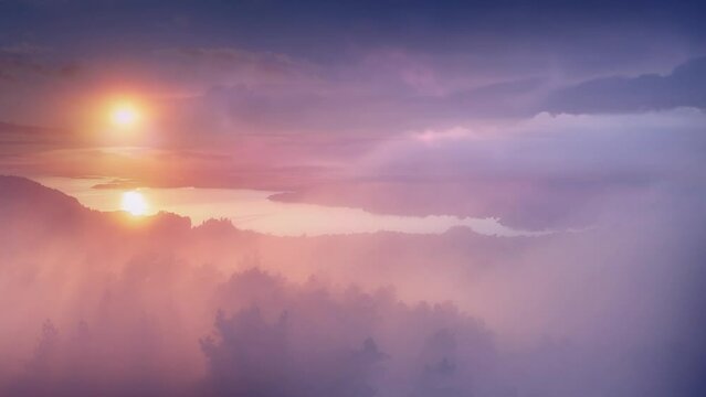 Aerial shot of beautiful, coloured misty sunset with clouds, camera moves into amazing, epic landscape of sunset at sea