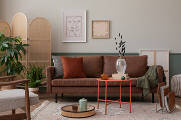 Warm and cozy composition of living room interior with mock up poster frame, brown sofa, beige rug, orange coffee table, wooden partition wall and personal accessories. Home decor. Template.