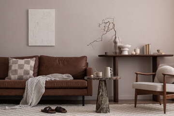 Creative composition of warm and cozy living room interior with mock up poster frame, brown sofa, round coffee table, boucle armchair, simple consola and personal accessories. Home decor. Template.