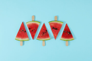 Watermelon fruit sliced with wood ice cream stick on blue background. Watermelon ice cream. Summer concept.