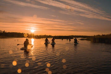 Stand up paddle boarding or standup paddleboarding on quiet lake at sunrise with beautiful colors...