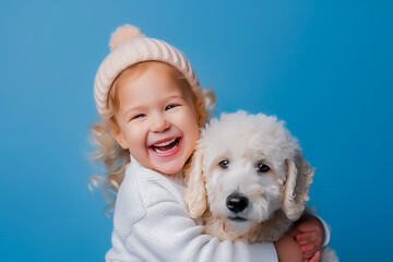 a happy little girl with curly blonde hair in a blue sweater, hugs a fluffy dog and laughs. Winter concept