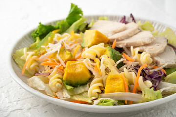 Fresh avocado lettuce salad bowl with chicken meat in a plate on white table background.