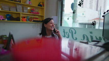 A Pet Shop owner speaking on phone with customer behind counter. Authentic real life local small...