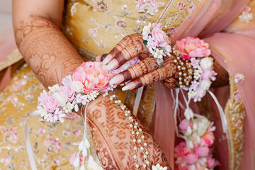 Fototapeta premium The hands of an Indian bride are decorated with Indian-style henna flowers and patterns. Hands of the bride close-up with patterns and ornaments in traditional Indian style top view patterns