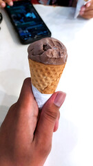 A cone of pretty chocolate ice cream gelato in a hand